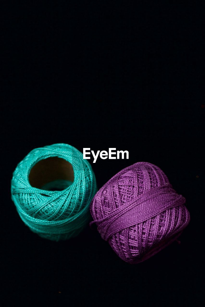 Purple and turquoise string spools against black background
