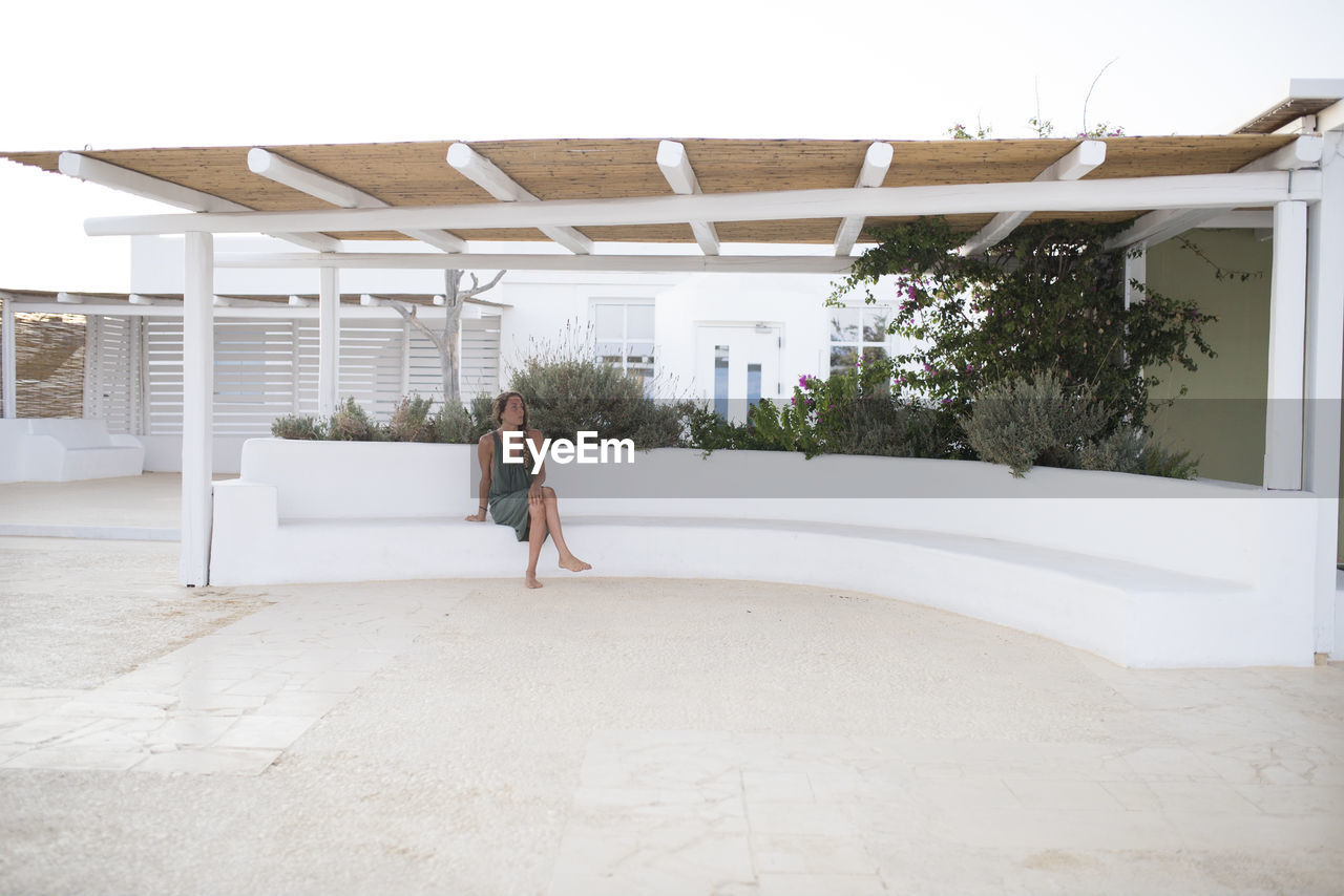 FULL LENGTH OF WOMAN WITH BUILDING IN BACKGROUND