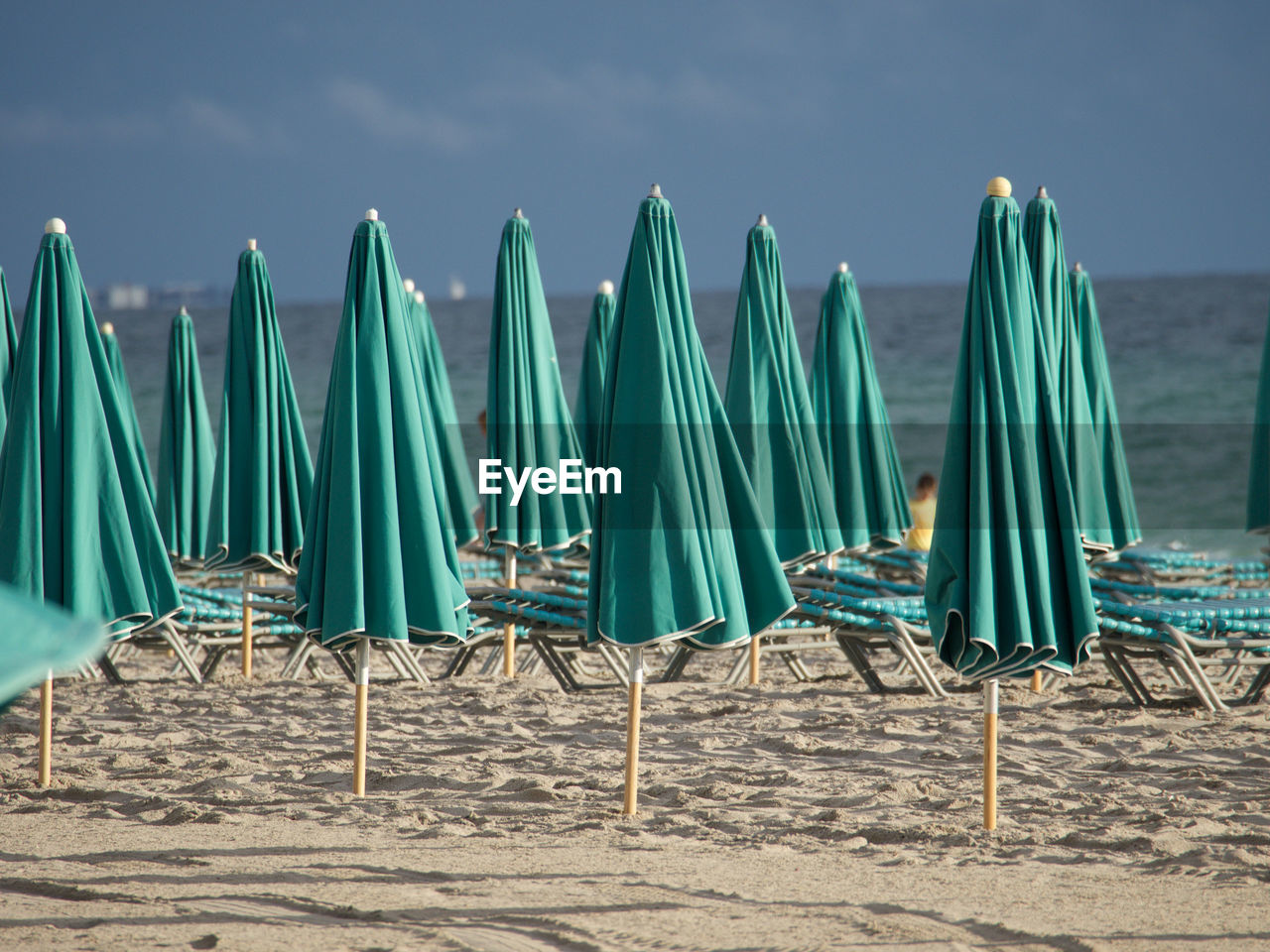 Deck chairs on beach against sky