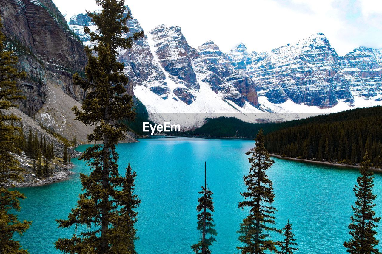 Scenic view of moraine lake by mountains against sky during winter