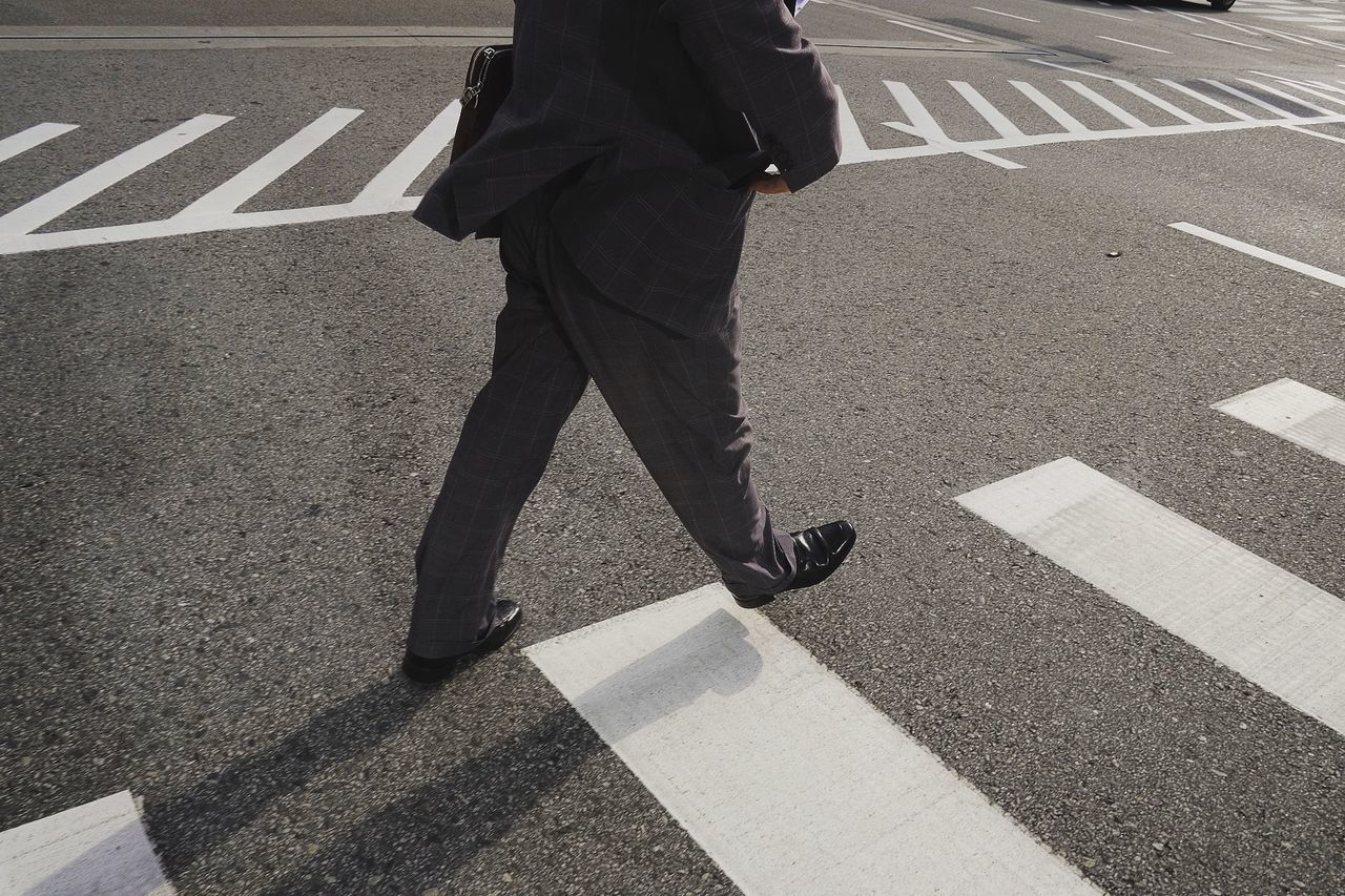 Low section of man walking on road