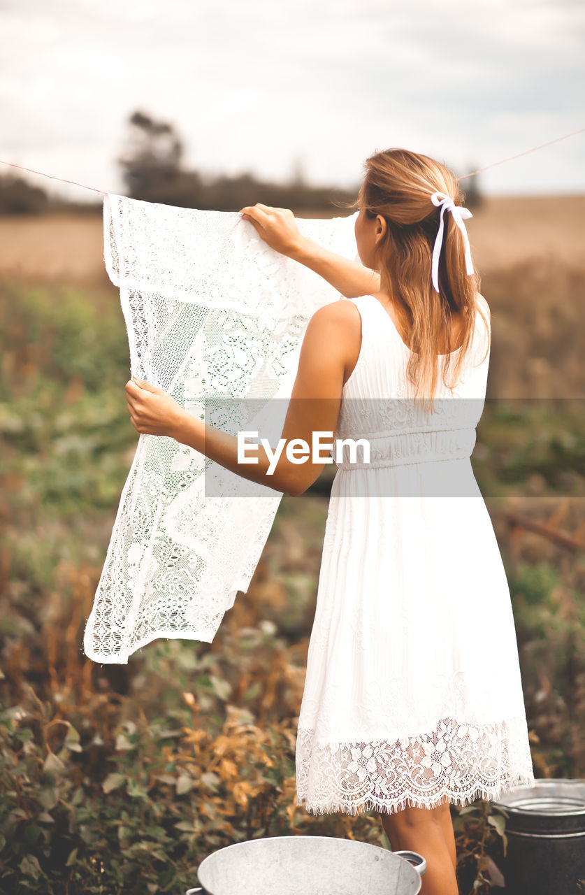 Woman hanging up laundry outdoor in a sunny day.