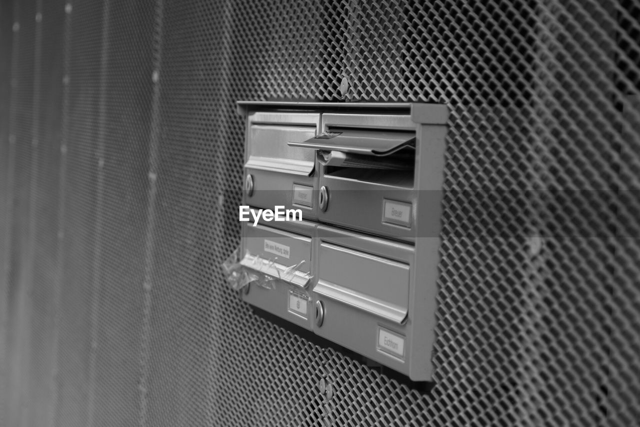 Mail in mailbox on metallic patterned wall at building