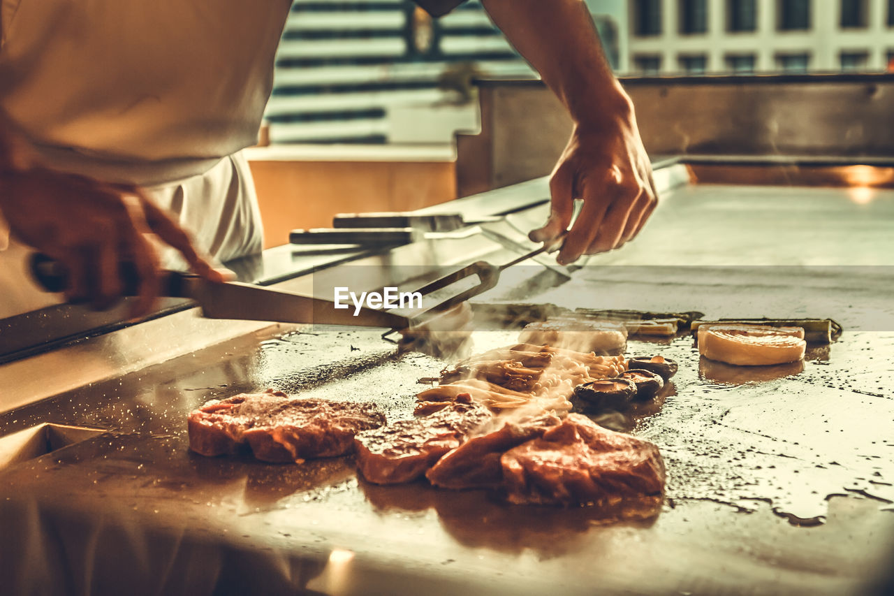 MIDSECTION OF PERSON PREPARING FOOD AT TABLE