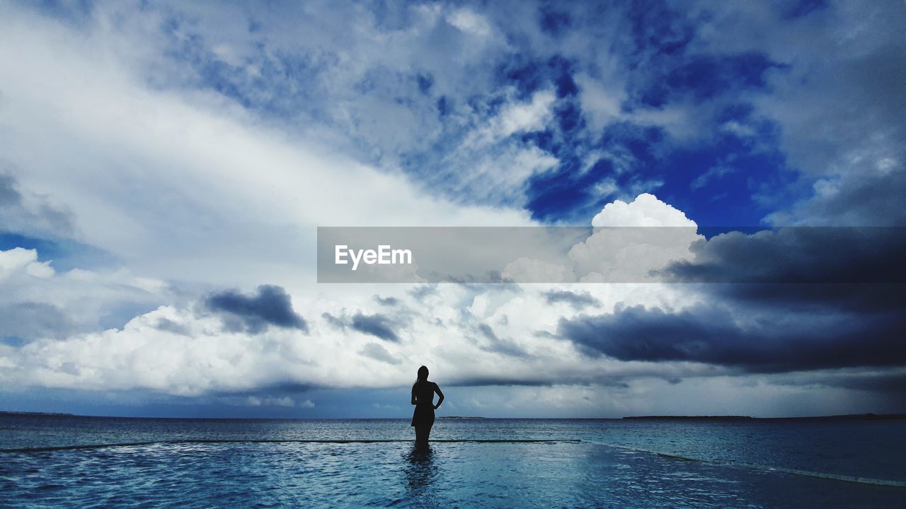 SILHOUETTE MAN STANDING IN SEA AGAINST SKY