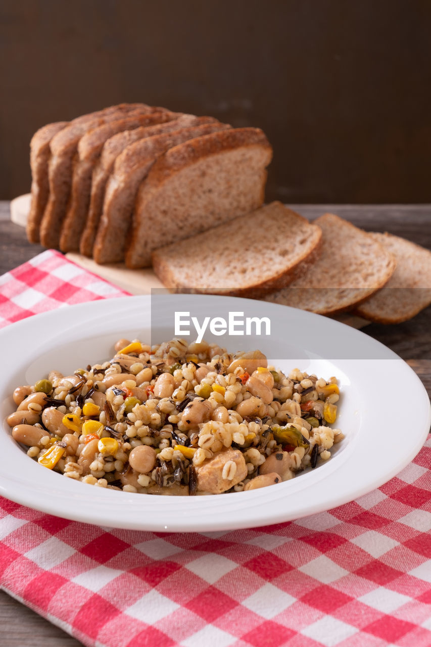 Spelled, chickpea, tuna and corn salad arranged on rustic table with bread