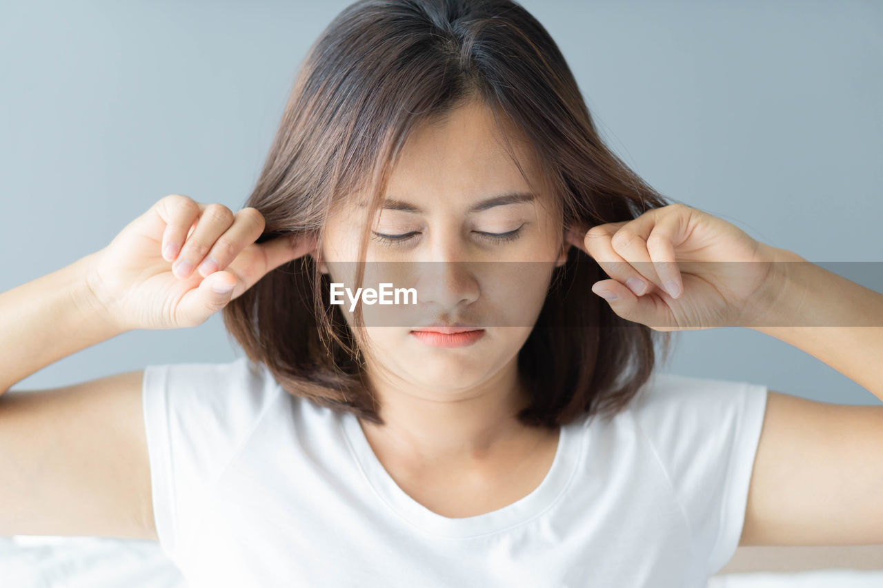 Close-up of angry woman covering ears at home