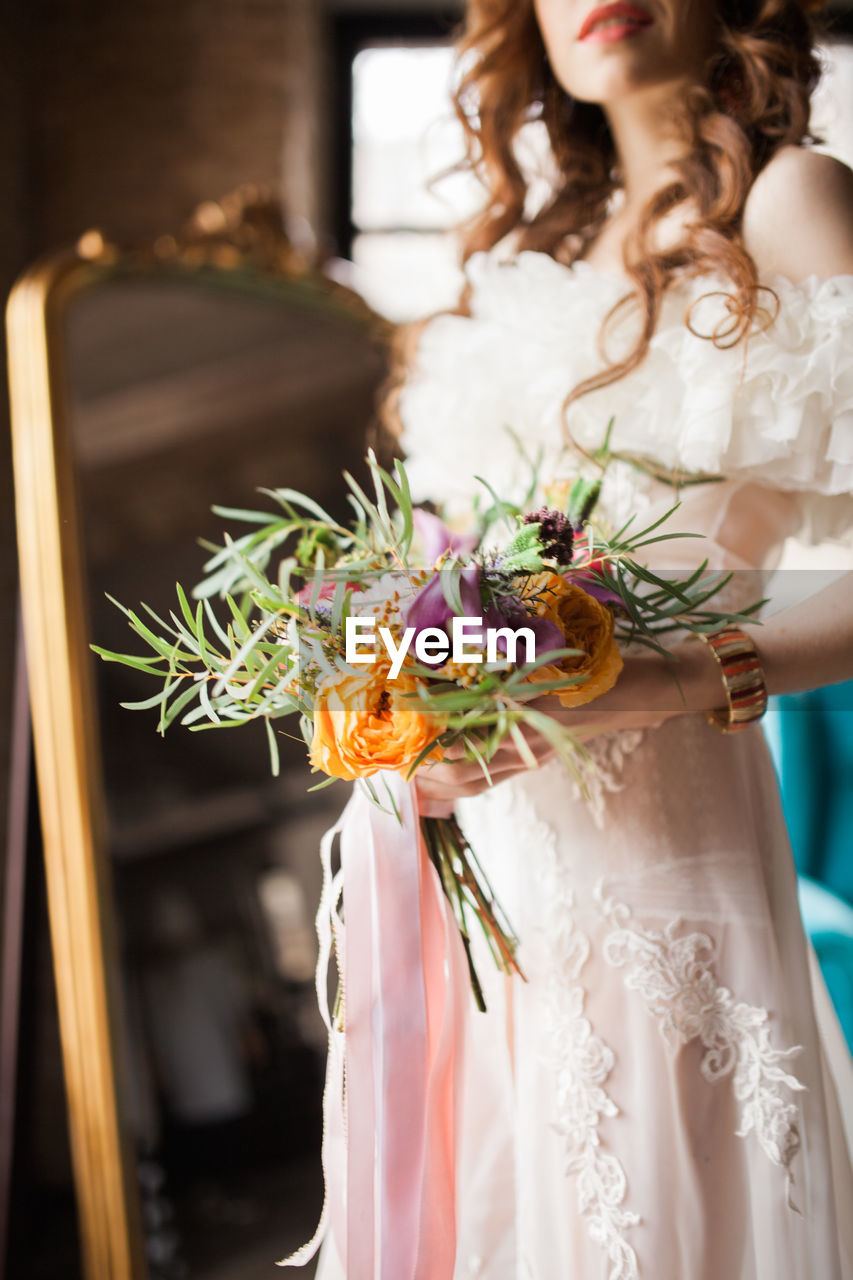 Redhead bride in dress holding wedding bouquet and smiling. wedding day concept