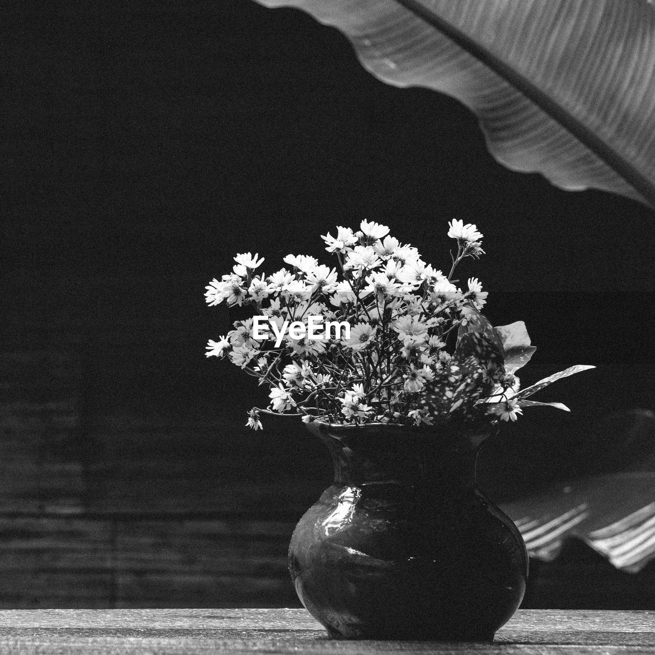 CLOSE-UP OF FLOWER VASE ON TABLE AGAINST WHITE WALL