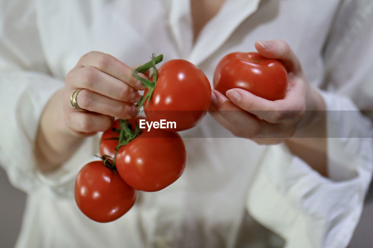 CLOSE-UP OF CHERRY TOMATOES IN HAND