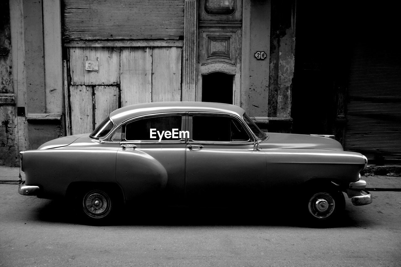 car, vehicle, land vehicle, mode of transportation, motor vehicle, transportation, retro styled, automobile, vintage car, architecture, automotive exterior, antique car, built structure, black and white, building exterior, city, old, street, no people, luxury vehicle, monochrome, day, monochrome photography