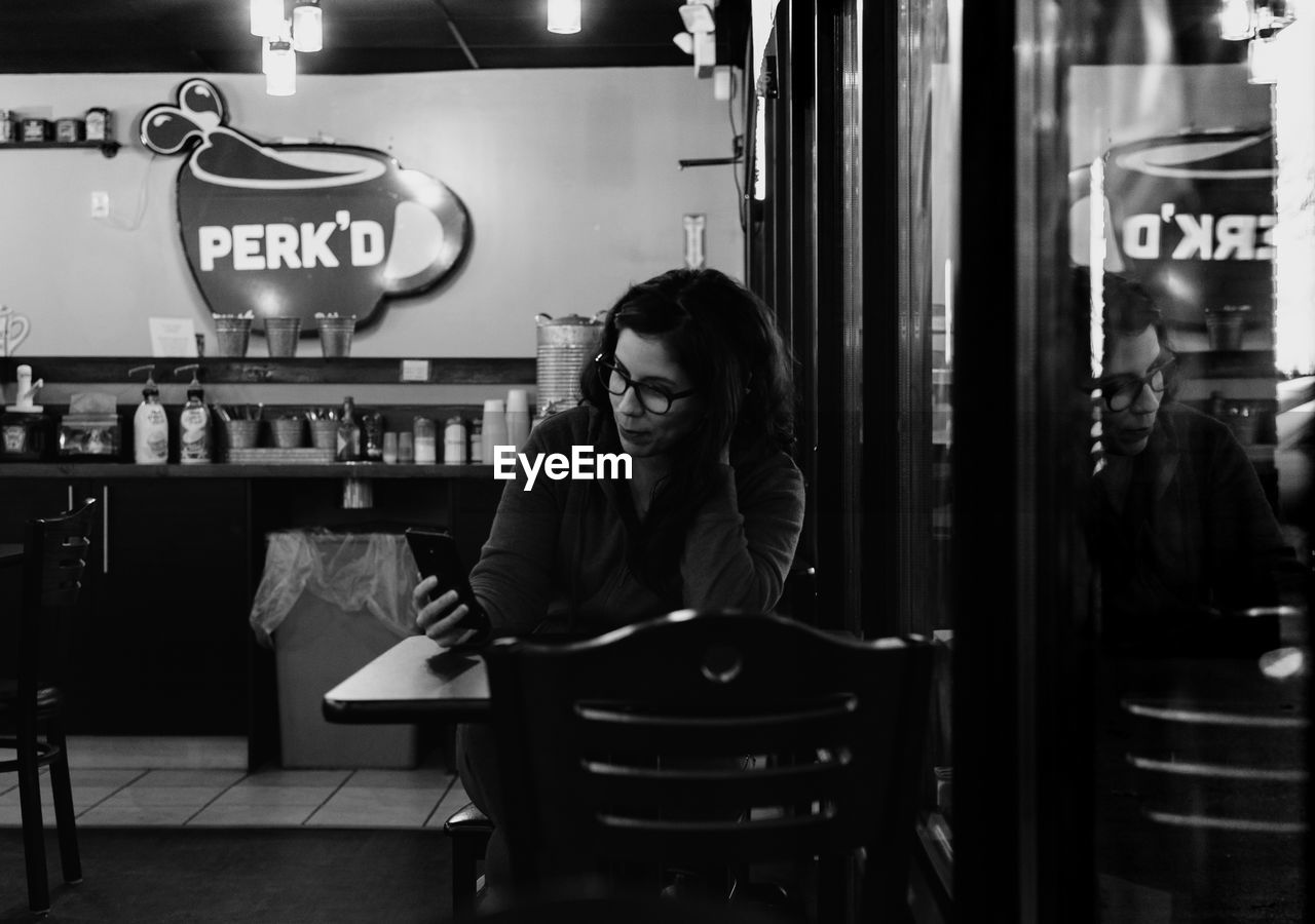 Woman using mobile phone while sitting in cafe