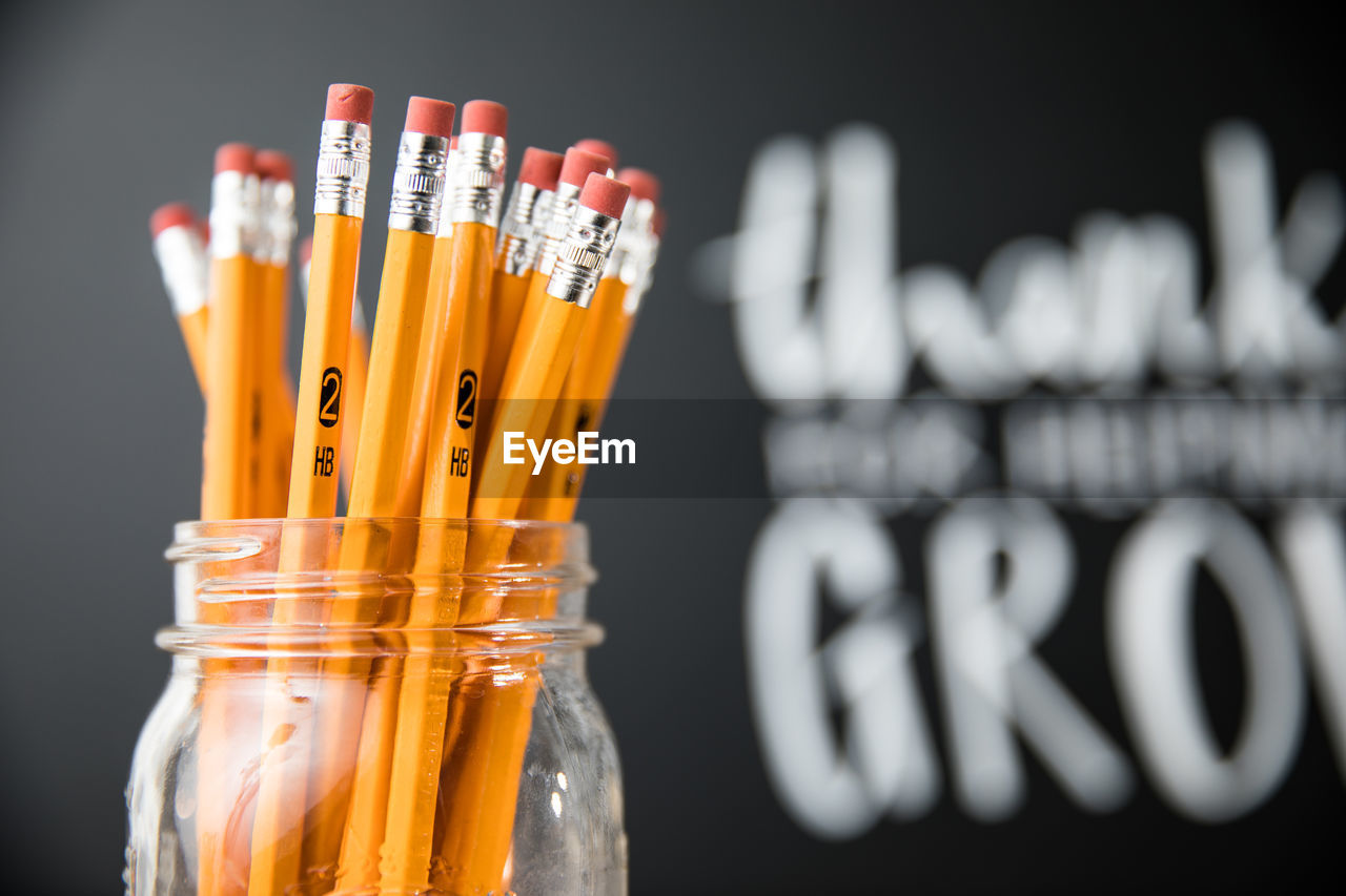 Close-up of pencils in jar against blackboard