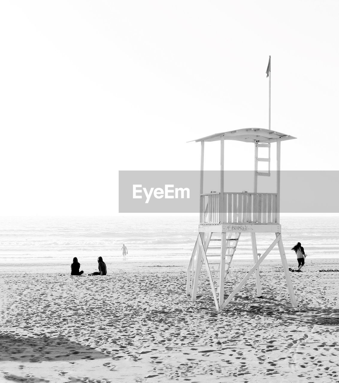 People and lifeguard hat at beach against clear sky