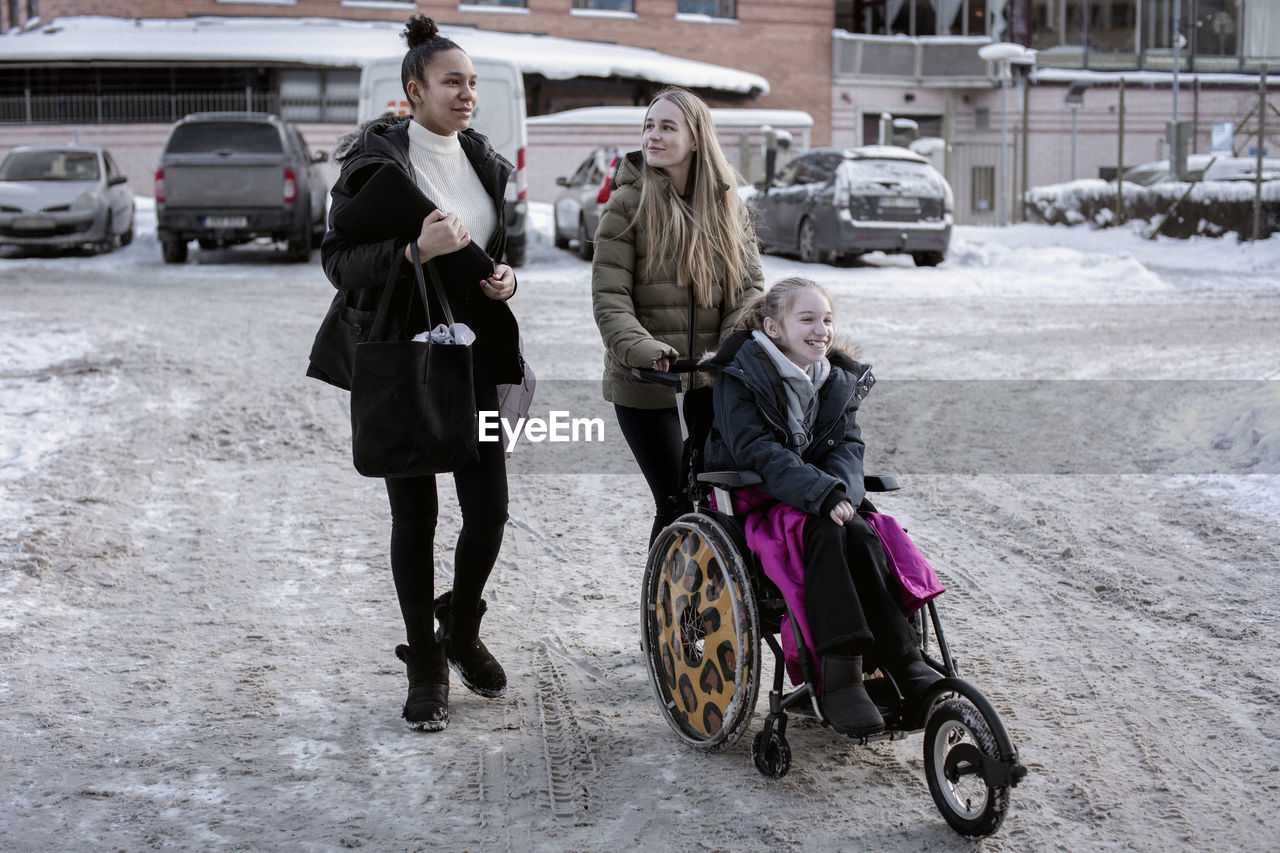 Women pushing girl on wheelchair