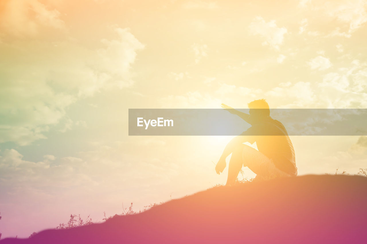 SILHOUETTE MAN STANDING ON MOUNTAIN AGAINST ORANGE SKY