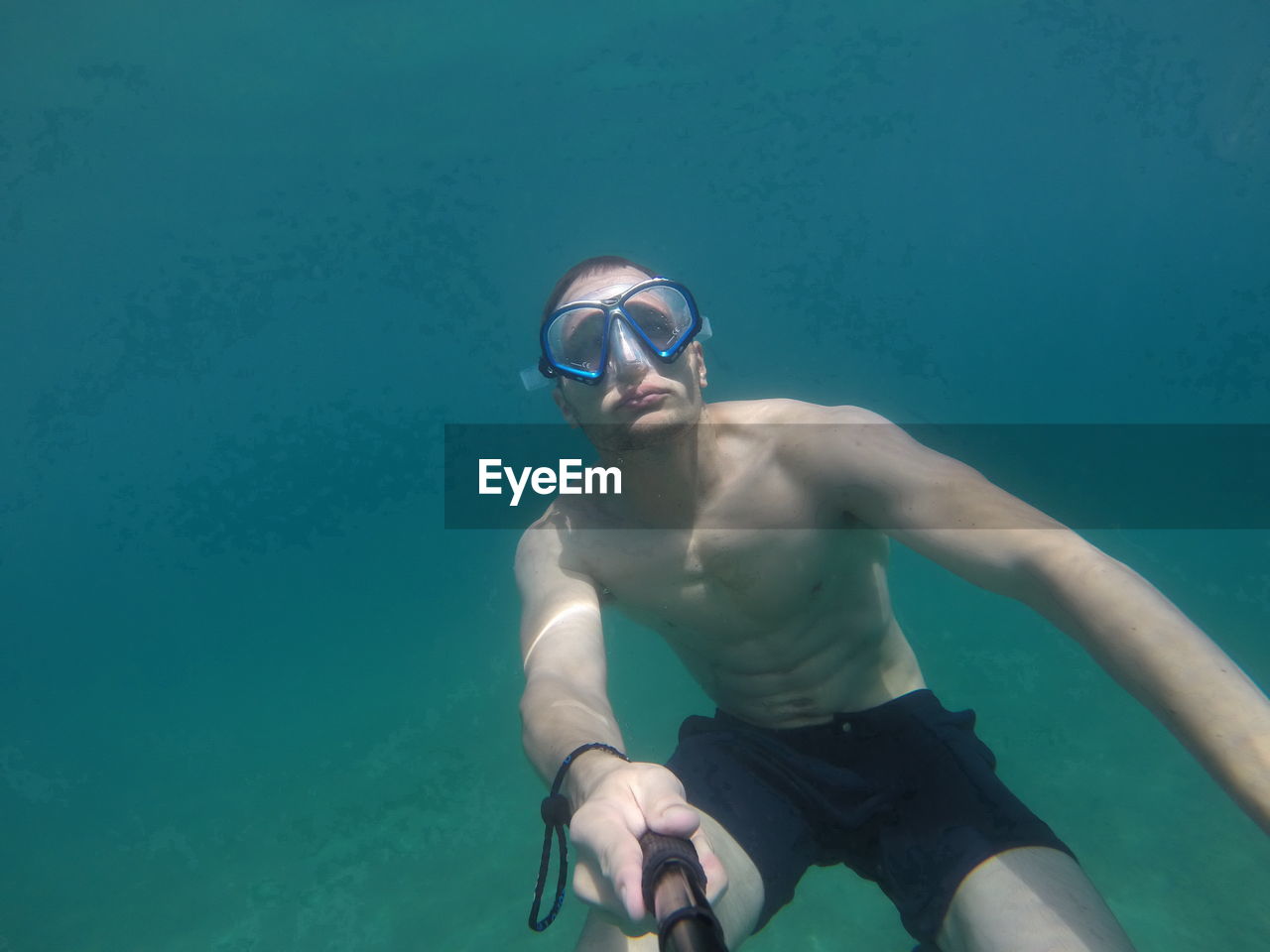 Shirtless man taking selfie in sea