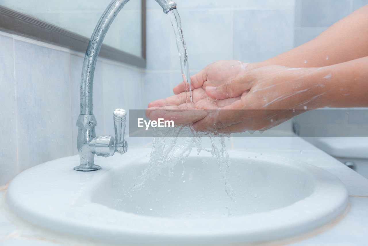 CROPPED IMAGE OF PERSON HAND WITH WATER FAUCET