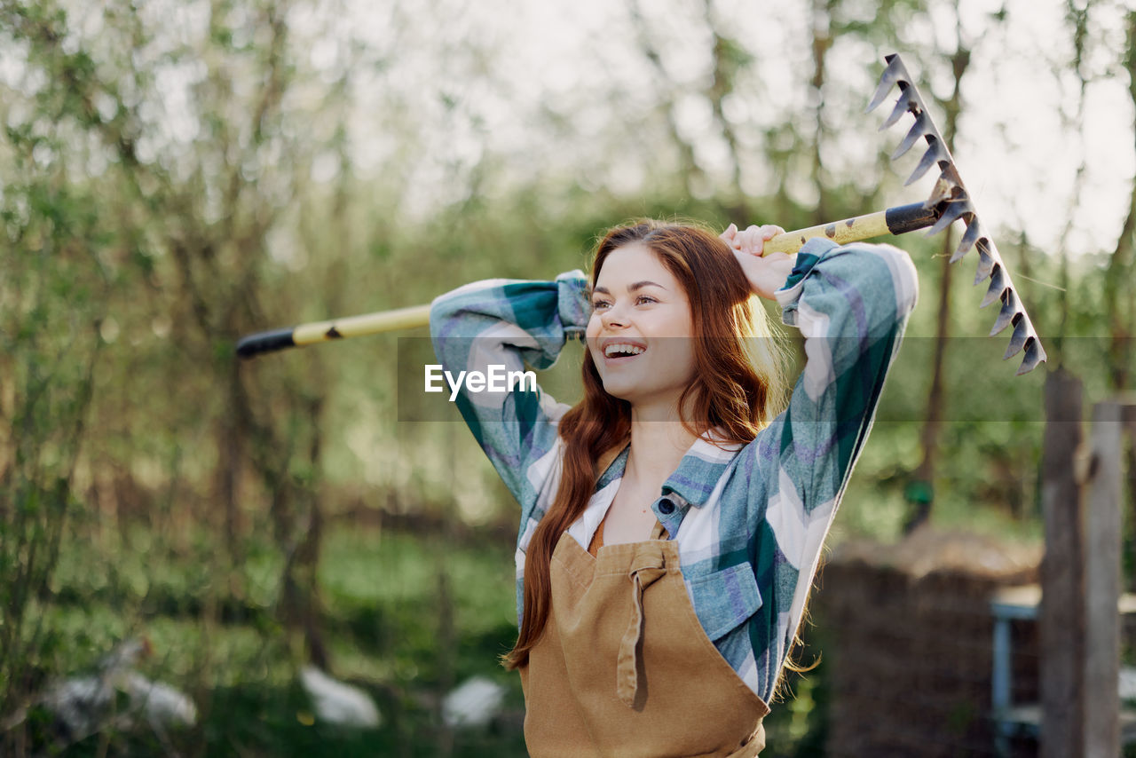 Portrait of young woman standing against trees