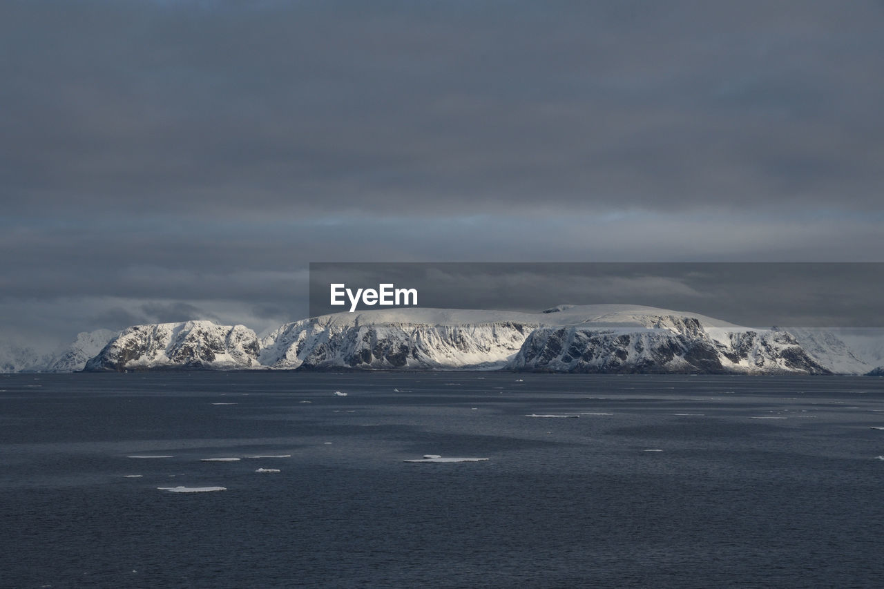 Scenic view of sea against snow covered landscape