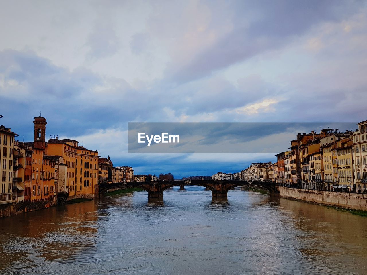 BRIDGE OVER RIVER AMIDST BUILDINGS IN CITY