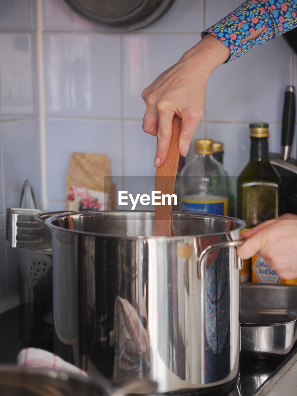 Cropped hand on woman cooking in container at kitchen