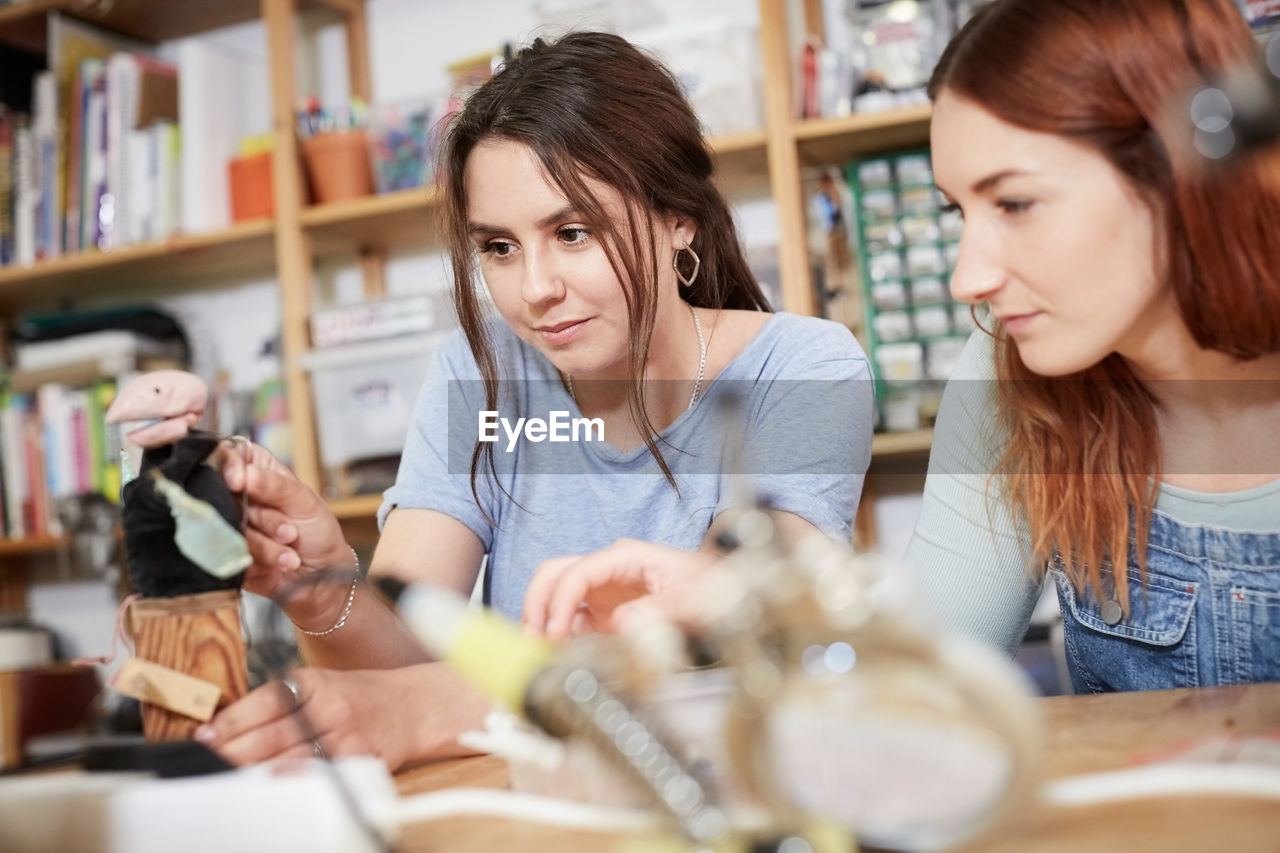 Young female technicians making model at table in workshop