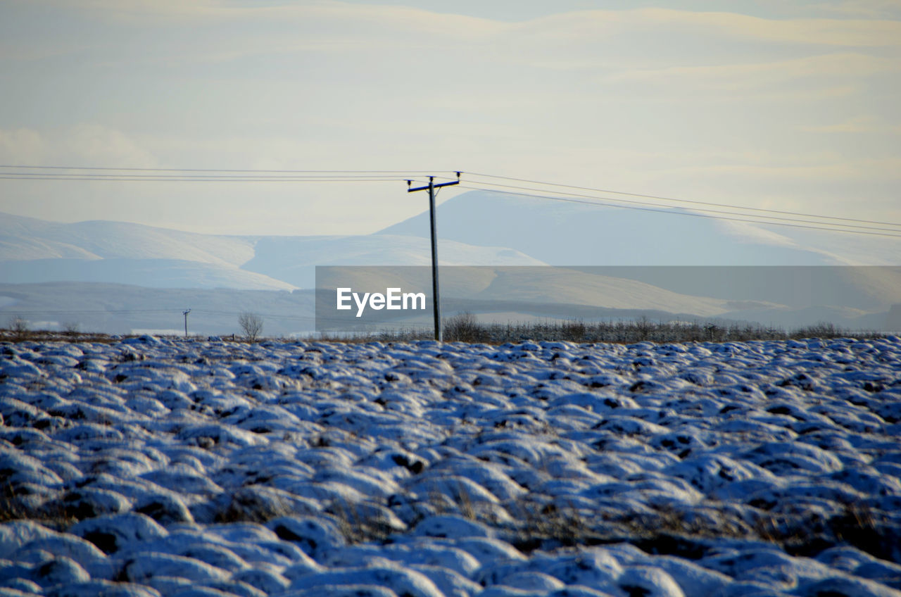 SNOW COVERED FIELD AGAINST MOUNTAINS