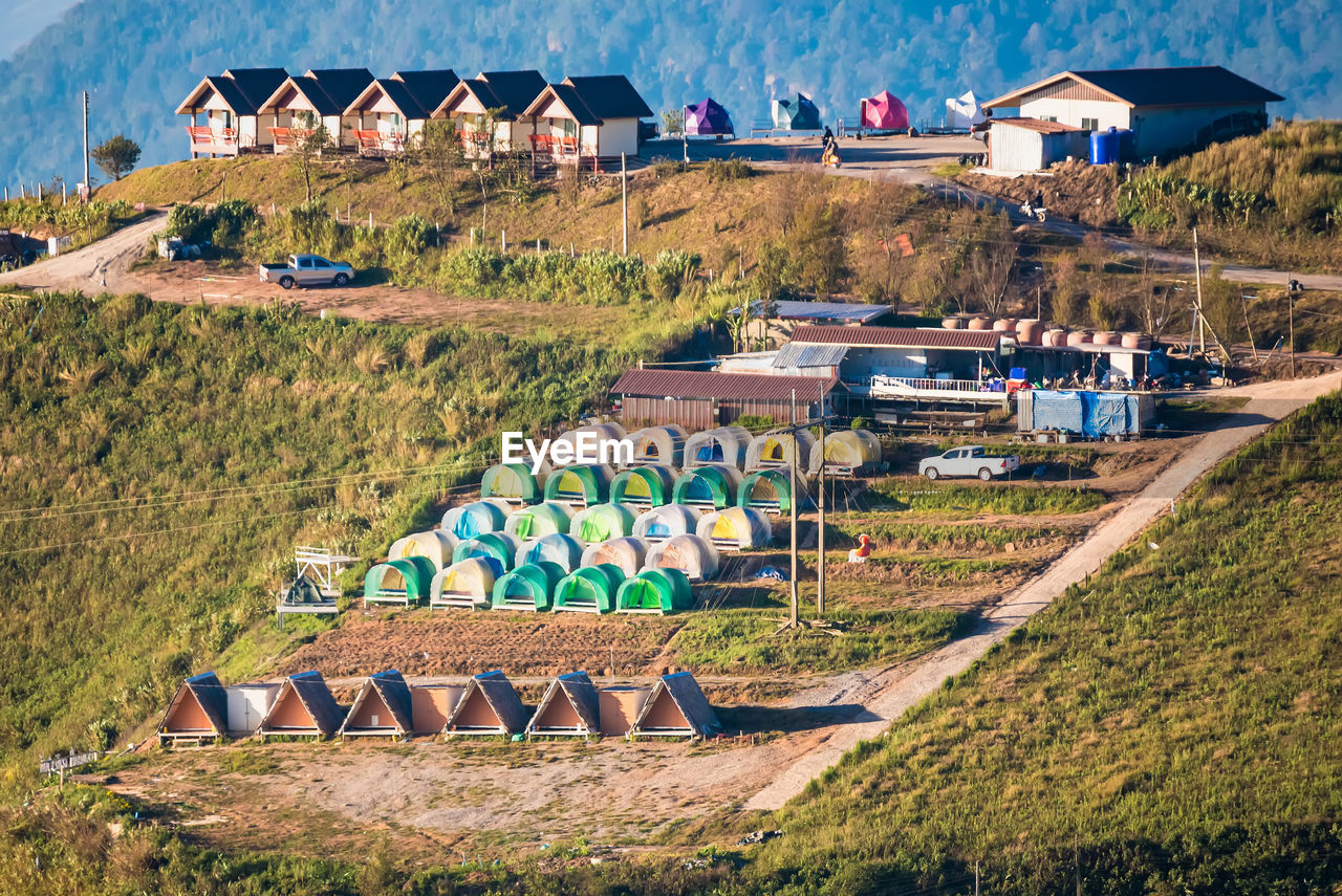 HIGH ANGLE VIEW OF HOUSES ON FIELD BY BUILDING