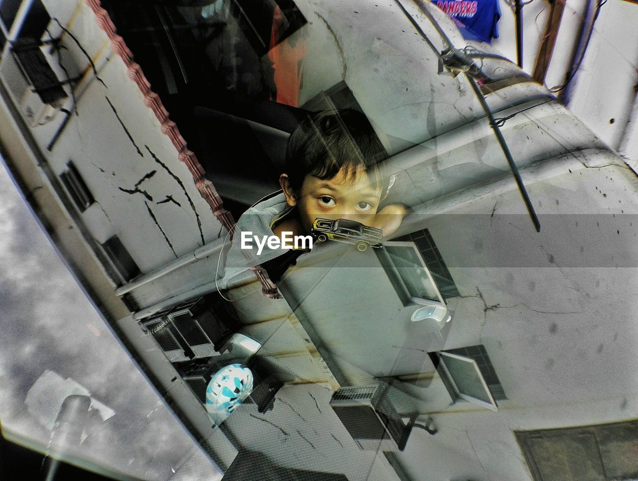 High angle portrait of boy seen through car windshield with reflection