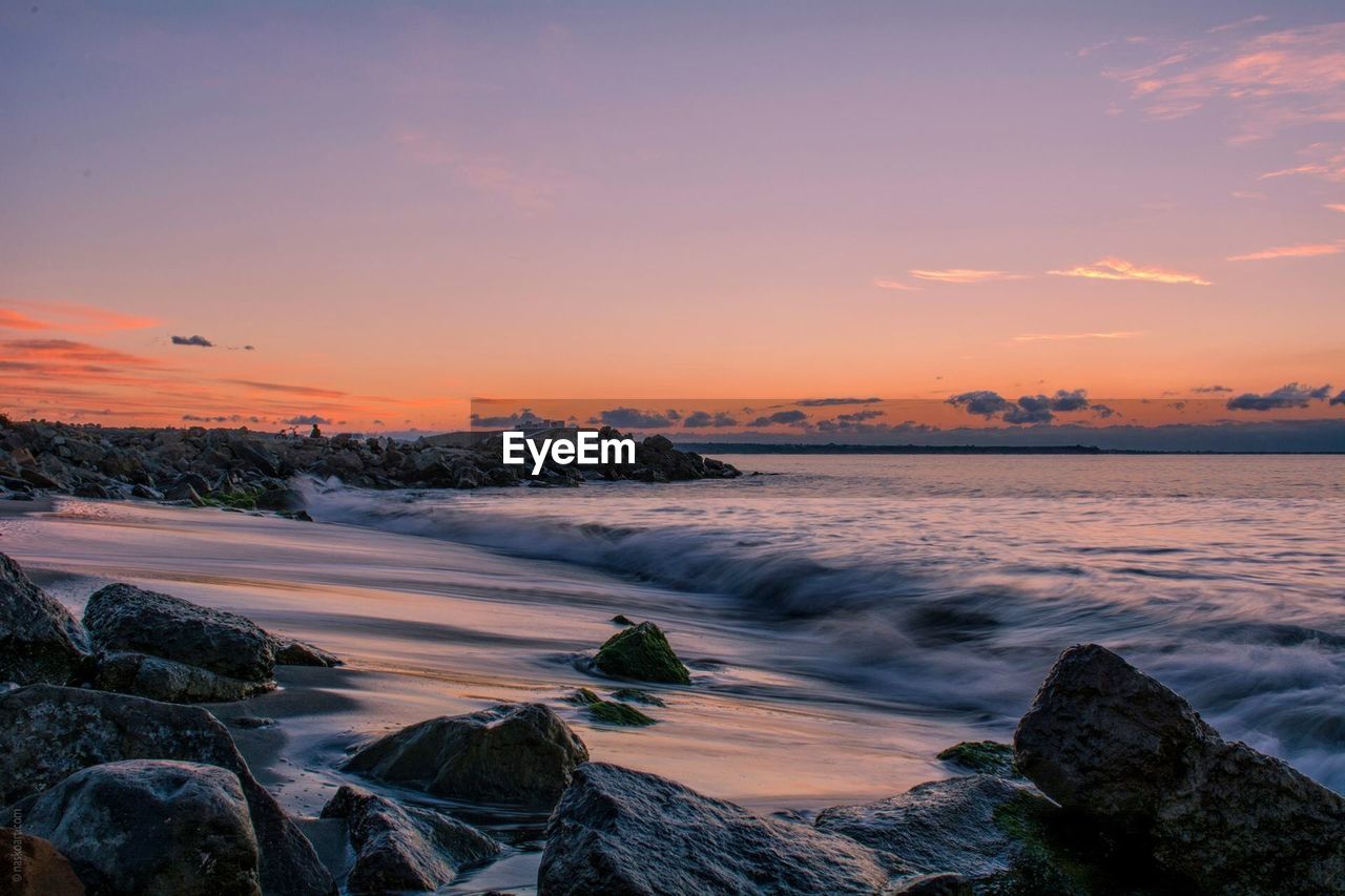Scenic view of sea against dramatic sky at sunset