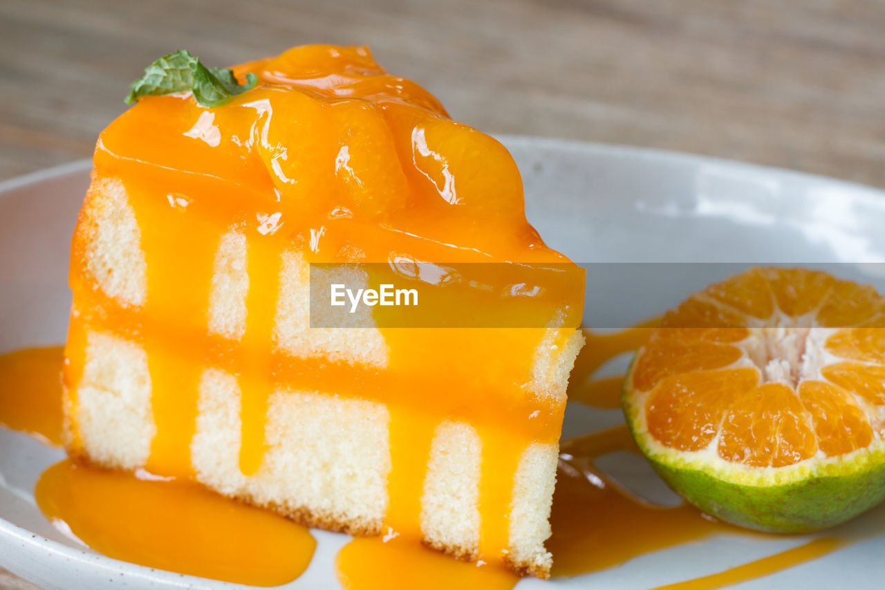 Orange cake with orange topping in wooden dish