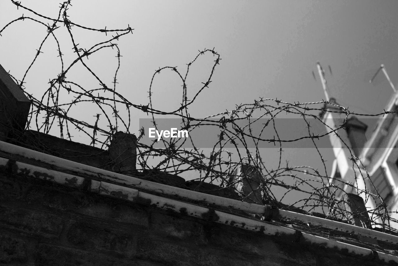 Low angle view of barbed wire against clear sky