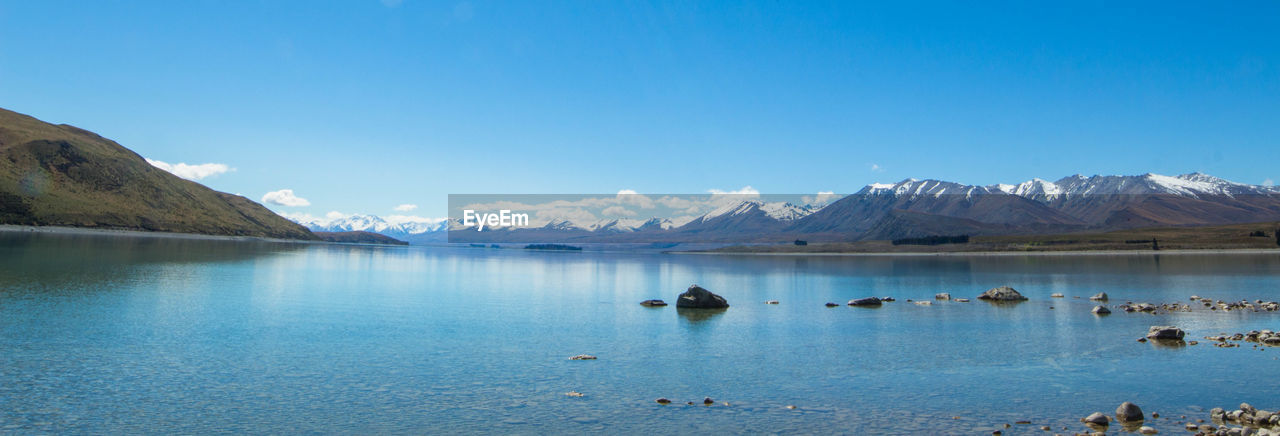 Scenic view of lake and mountains against blue sky