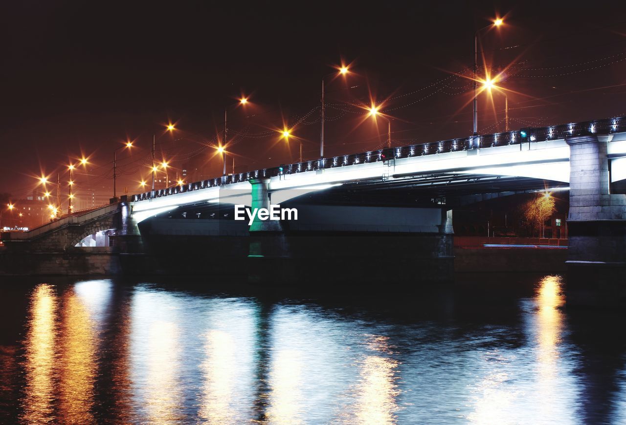 Illuminated bridge over river at night