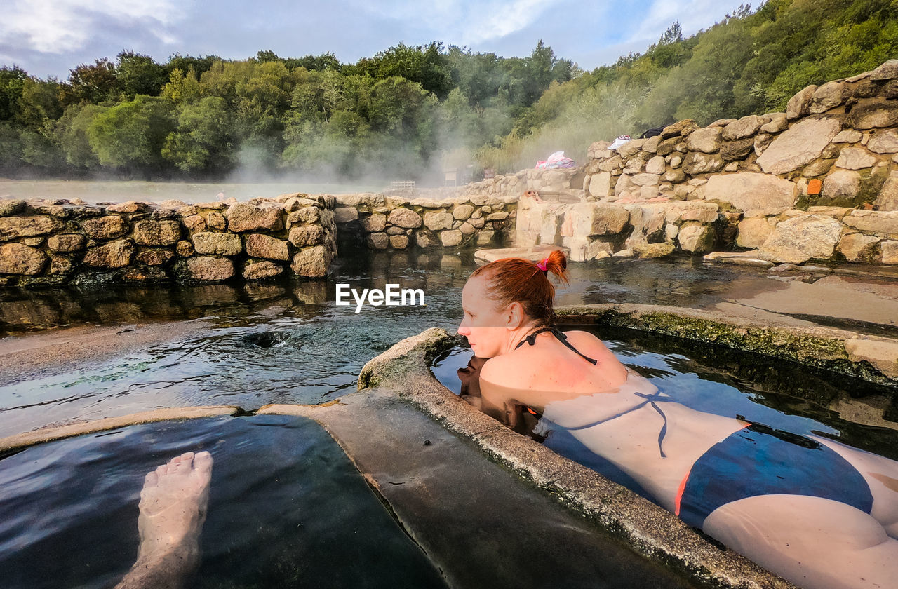 Woman wearing bikini while lying in hot spring