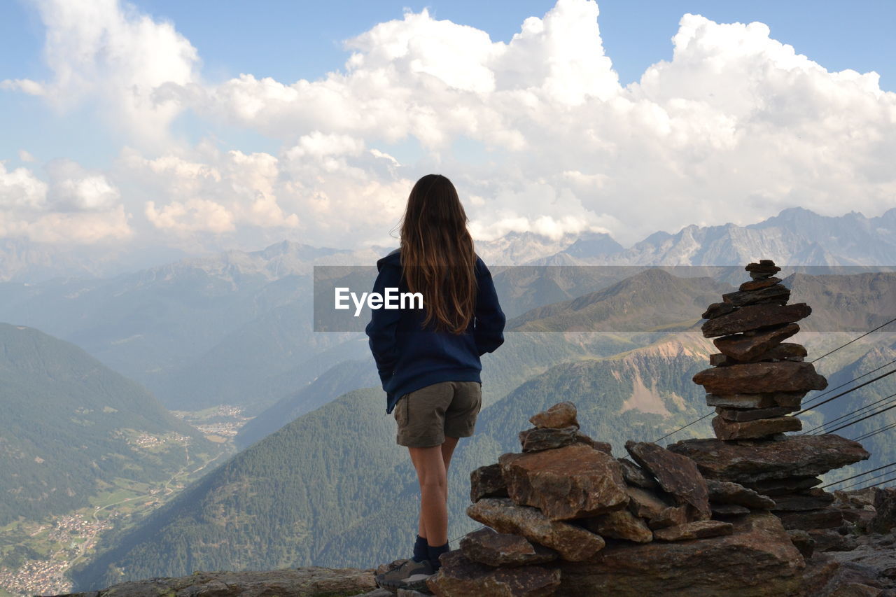 Girl standing on rock against sky