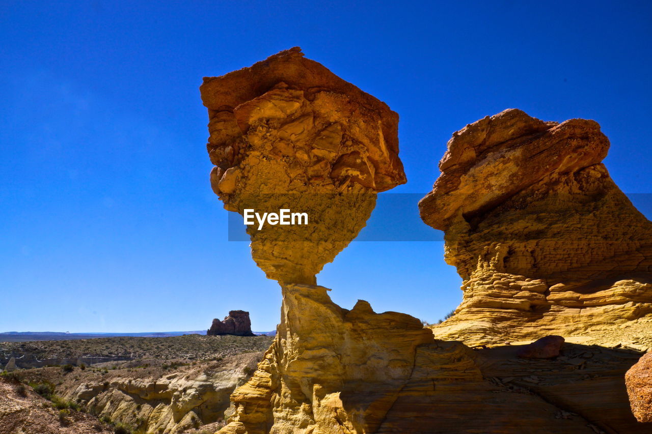 Rock formations on landscape against clear blue sky
