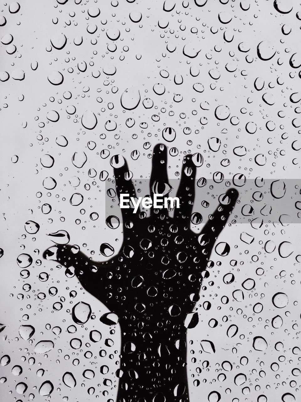 Close-up of hand seen through wet glass during rainy season