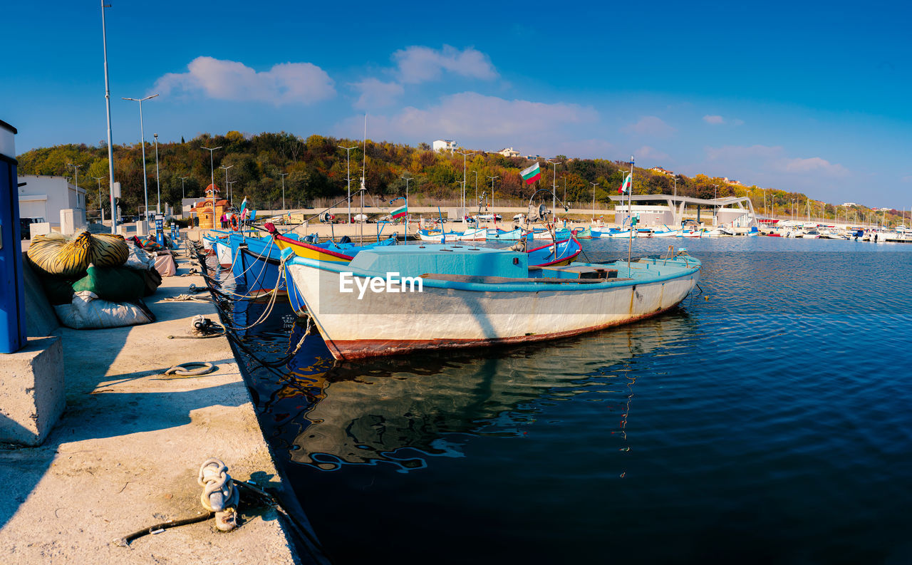 Boats moored in sea against blue sky