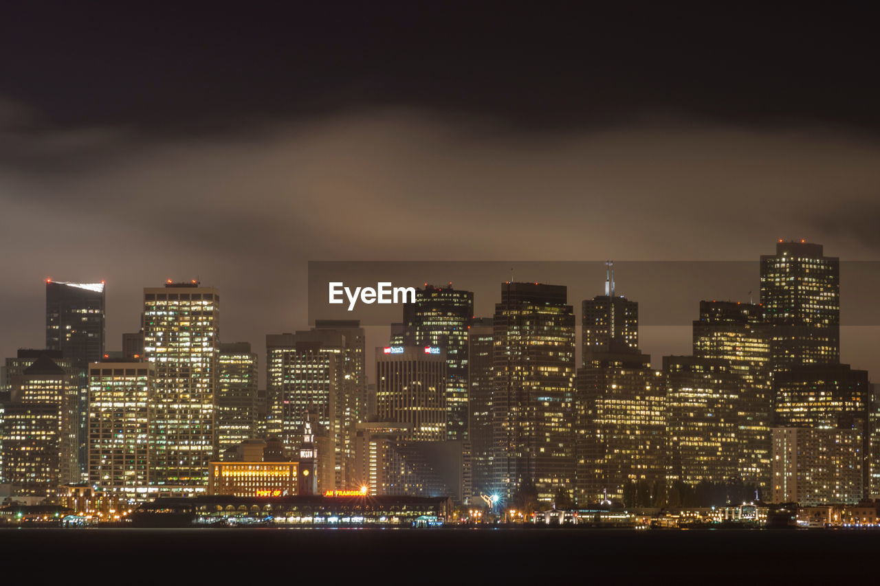 ILLUMINATED CITY BUILDINGS AGAINST SKY AT NIGHT