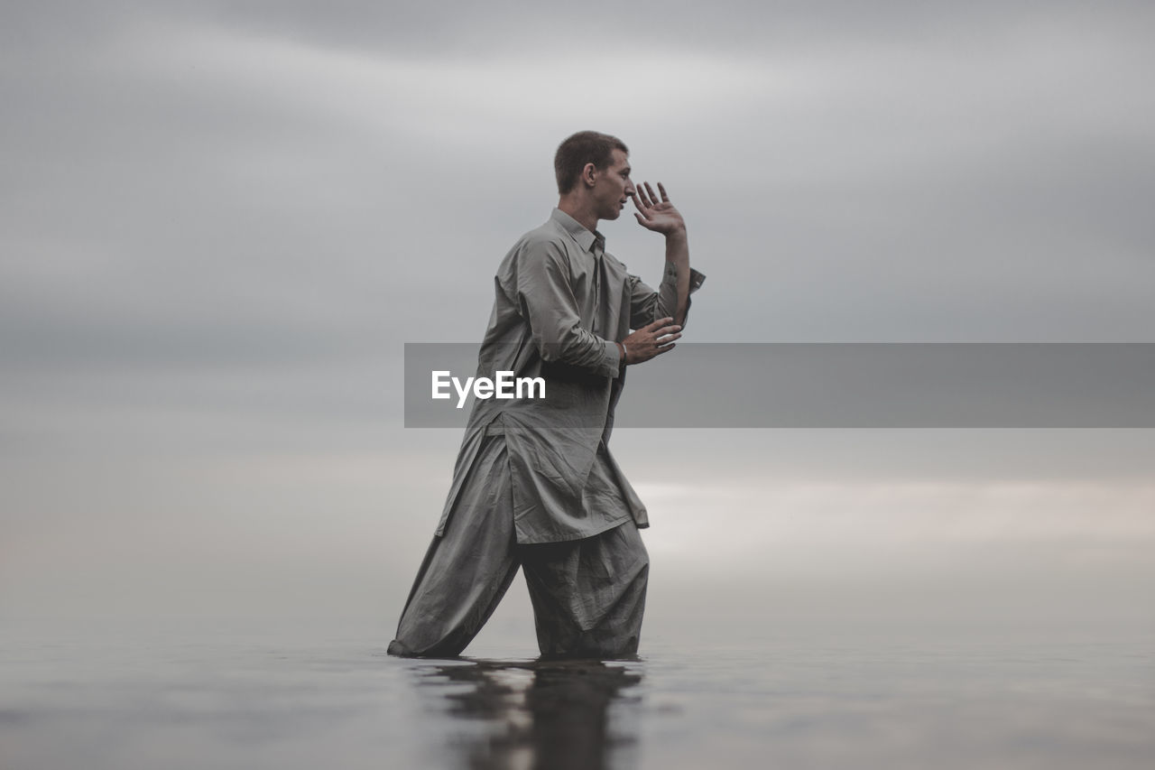 Man exercising in sea against sky