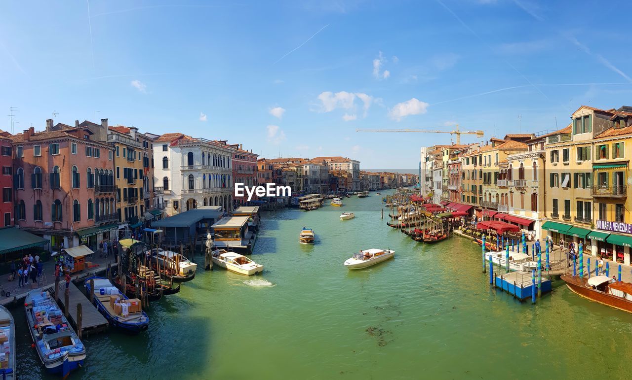 Boats moored in canal amidst buildings in city