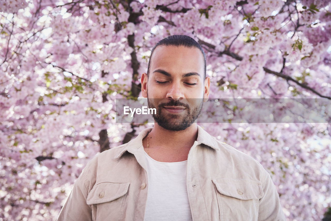 Young man standing under cherry blossom