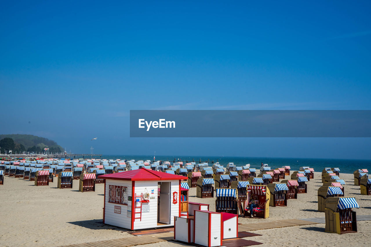 Hooded beach chairs on beach against clear sky