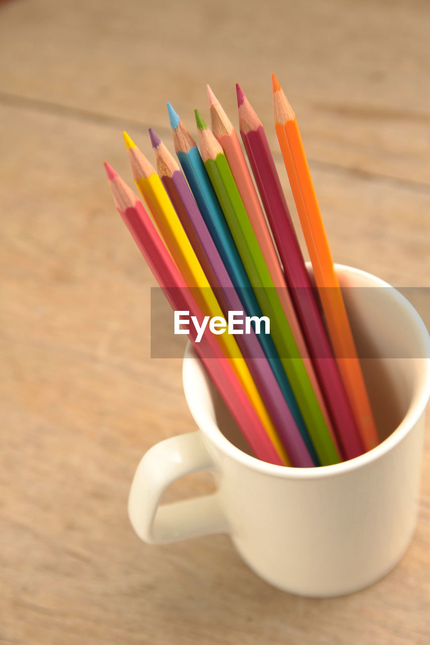 Close-up of colored pencils in cup on table