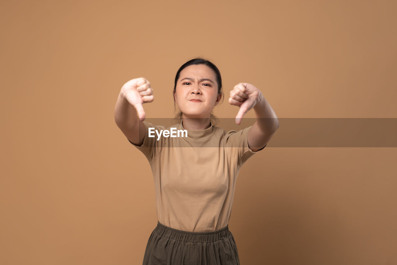 one person, studio shot, colored background, portrait, indoors, adult, happiness, front view, standing, smiling, young adult, arm, emotion, waist up, copy space, hand, arms raised, women, eyes closed, cheerful, human limb, gesturing, limb, positive emotion, looking at camera, finger, holding, casual clothing, lifestyles, fun, person, cut out