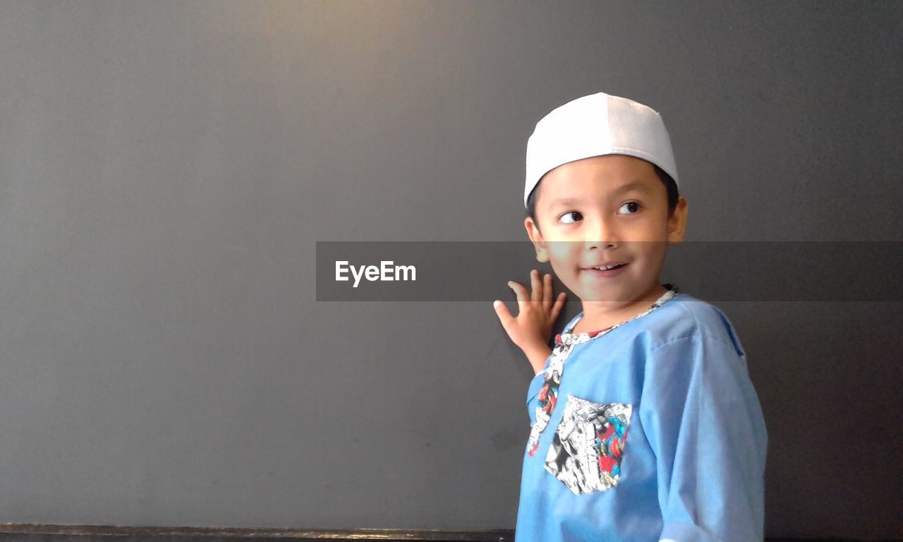 Smiling boy standing against wall