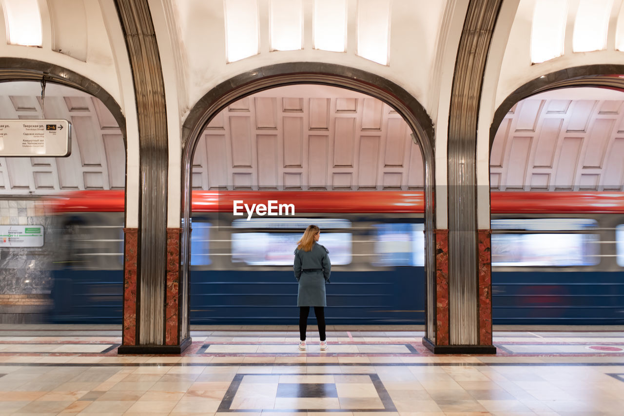 Woman in a blue coat at the metro station. departing train. motion blur 