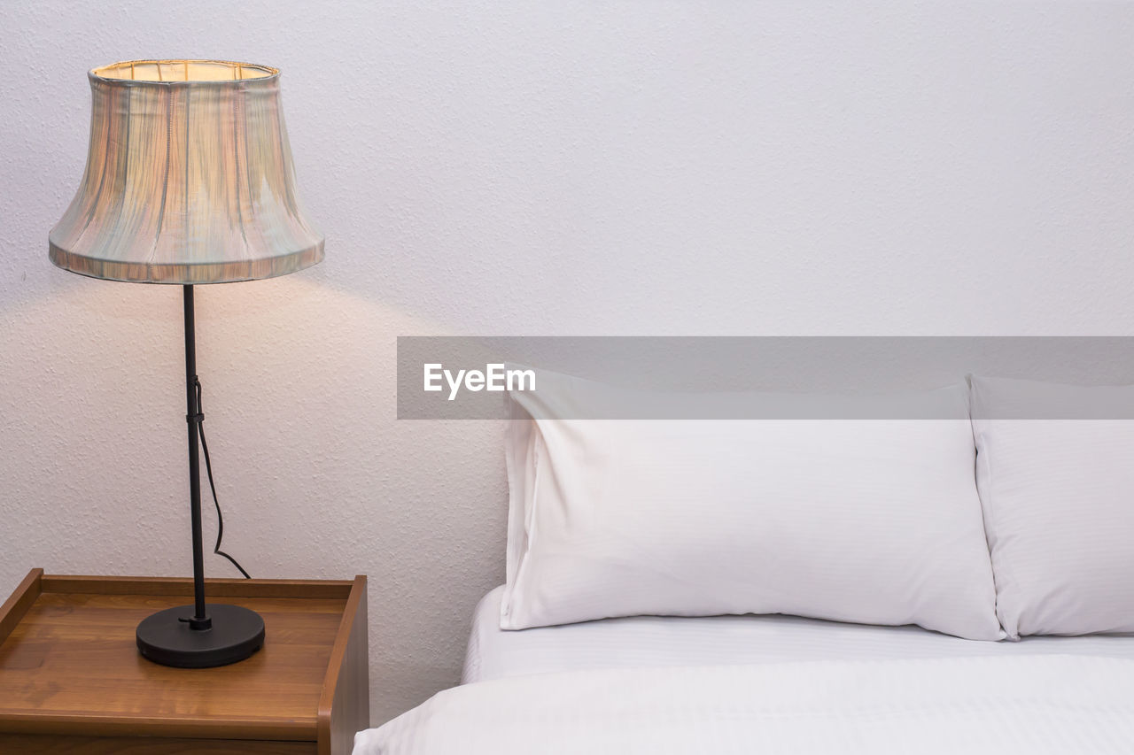 Electric lamp by bed against wall at home